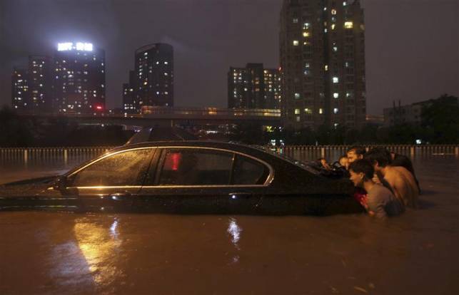 Photo de gens poussant une voiture dans une cité inondée