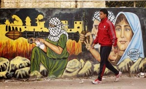 Palestinien passant devant mur porteur d'une représentation guerrière