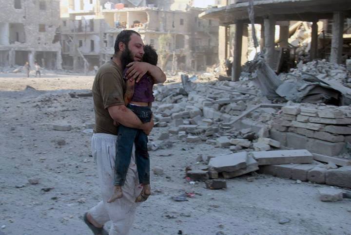 photo d'un père palestinien, au milieu de ruines, portant enfant victime