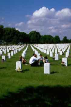 photo d'une famille se recueillant devant stèle dans un cimetière militaire