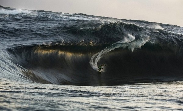 Photo de surfeur glissant sous une vague pers sombre.