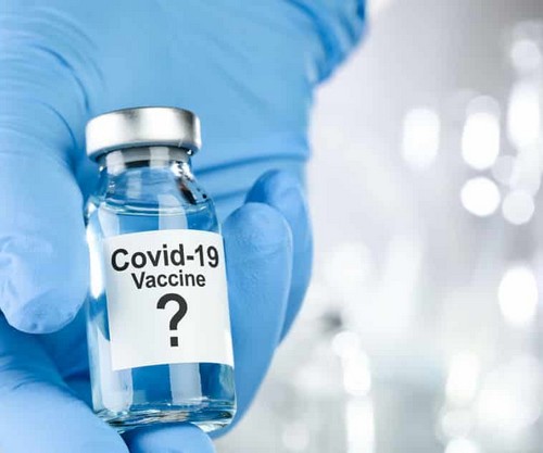 Photo de main gantée bleue montrant flacon vaccin covid-19 avec point interrogation.
