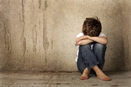 Photo de jeune enfant peiné, assis, prostré au pied d'un mur.