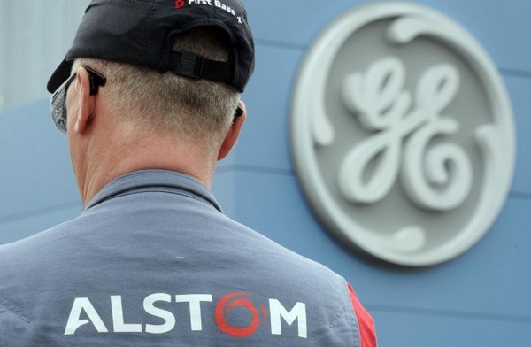 Photo de dos d-un ouvrier de Alstom devant logo symbole de General Electric.