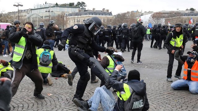 Photo de policier donnant coup de pied à manifestant Gilet Jaune au sol.