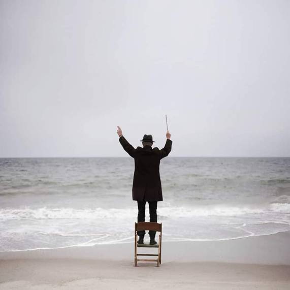 Photo insolite de chef orchestre donnant mesure devant Mer.