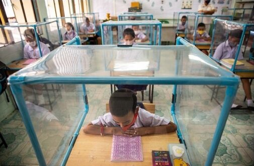 Photo d'écoliers séparés, dans cages de plastique.