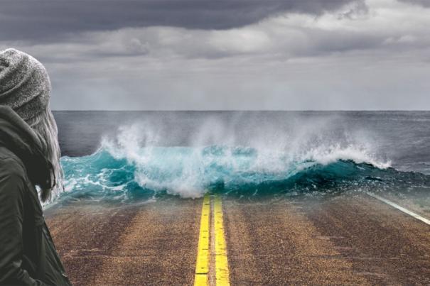 Image compose de vague submergeant une route avec humain de profil  gauche.