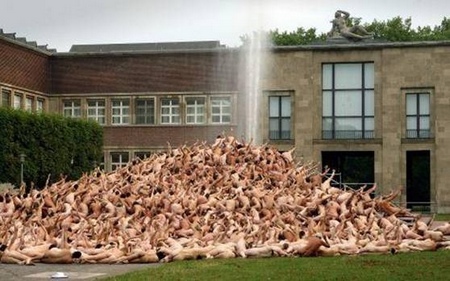 photo de Spencer Tunic, tas de corps nus levant le bras vers statue d'un dieu