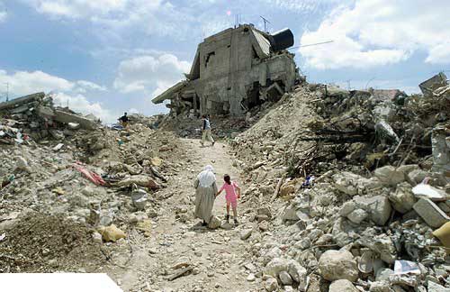 Photo de victimes palestiniennes marchant dans les ruines après attaque israélienne en avril 2002.