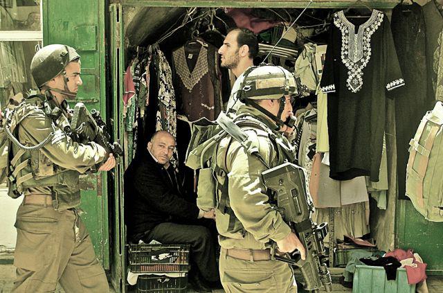 photo de soldats d'Israel, passant devant une échope, Gaza, été 2014