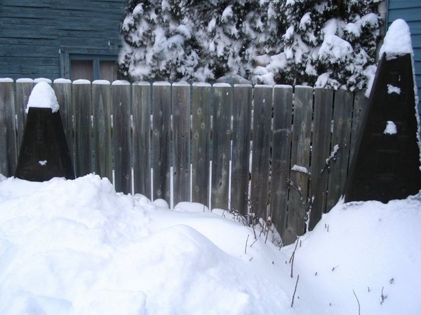 Photo de Odette BEAUDRY, montrant palissade et stles-pyramides tronques dans la neige.