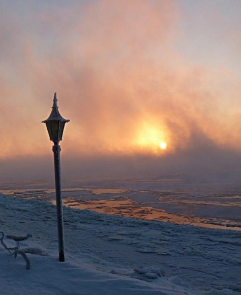 Photo de lampadaire au milieu de la glace dans l'aube naissante.