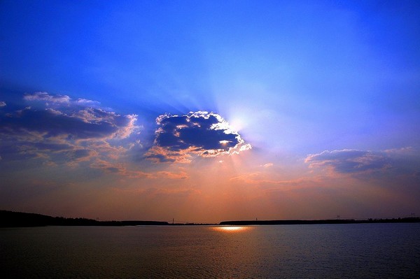Photo aube sur bassin portuaire, soleil derrière nuage.