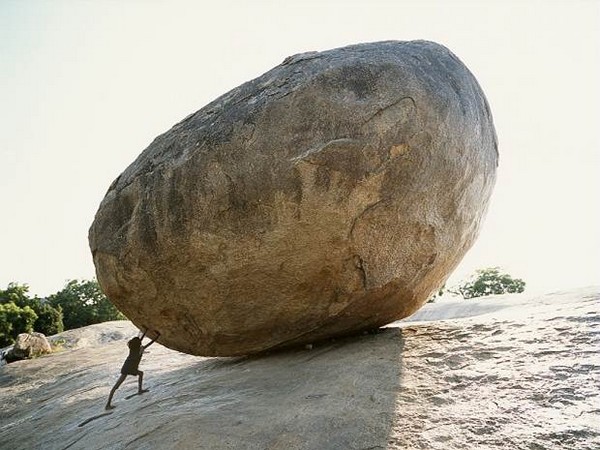 enfant essayant de pousser un énorme rocher en forme de patate