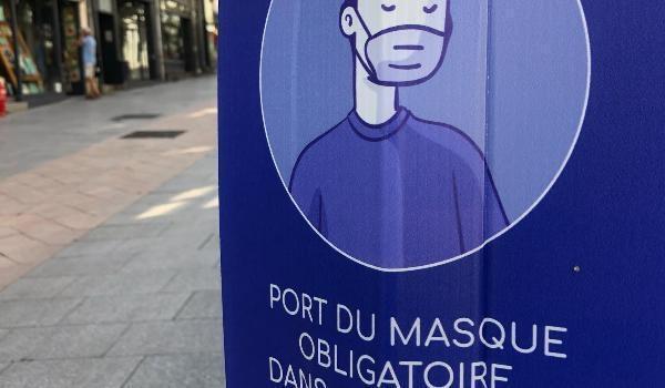 Photo de panneau bleu indiquant port du masque obligatoire dans rue quasi vide.